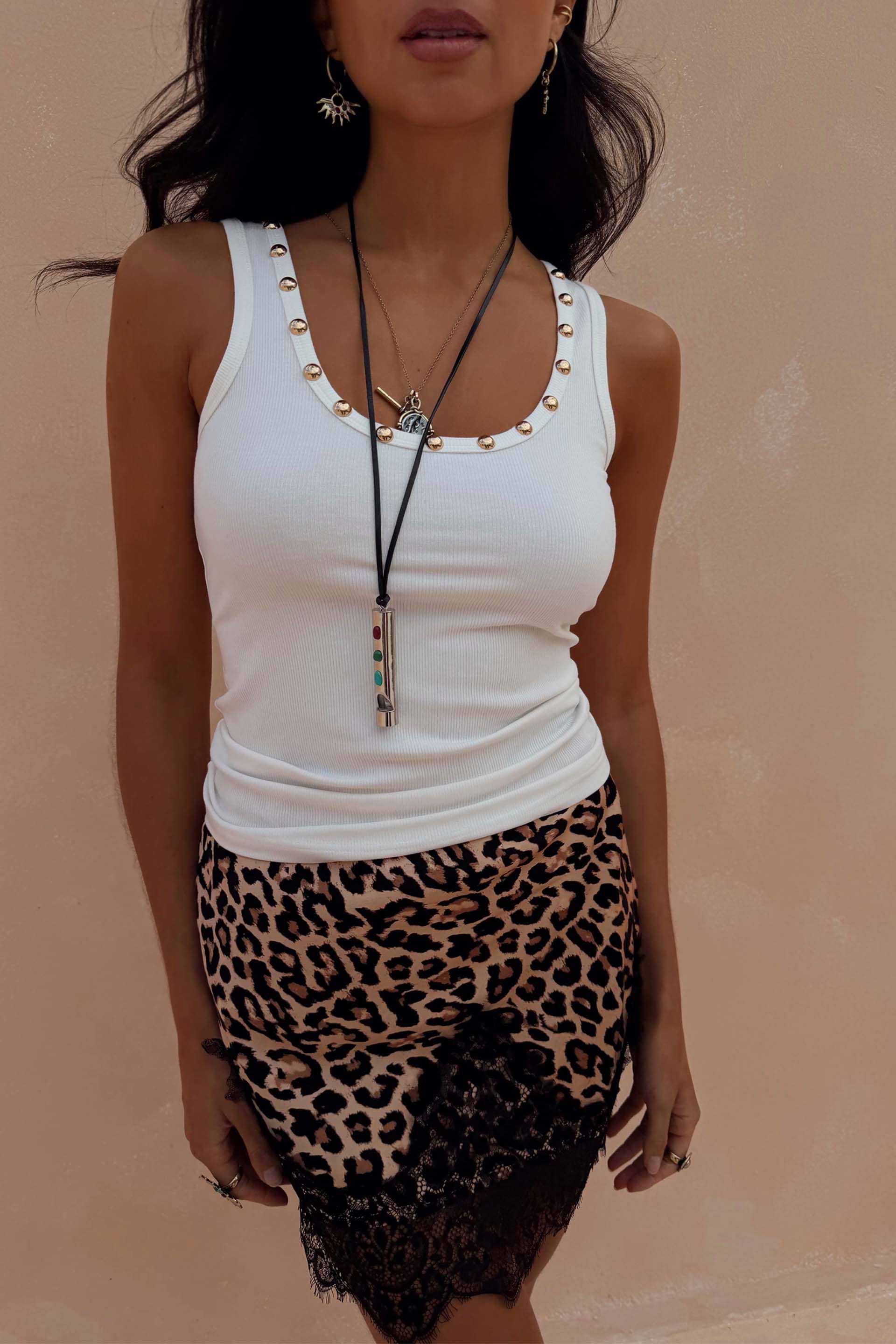 White ribbed vest with gold stud detailing along the neckline, styled with a leopard print lace skirt.