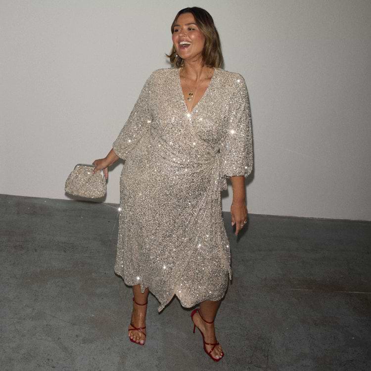 Silver Sequin Kira Wrap Dress with a multi-wear tie waist, red heels and a silver clutch bag.