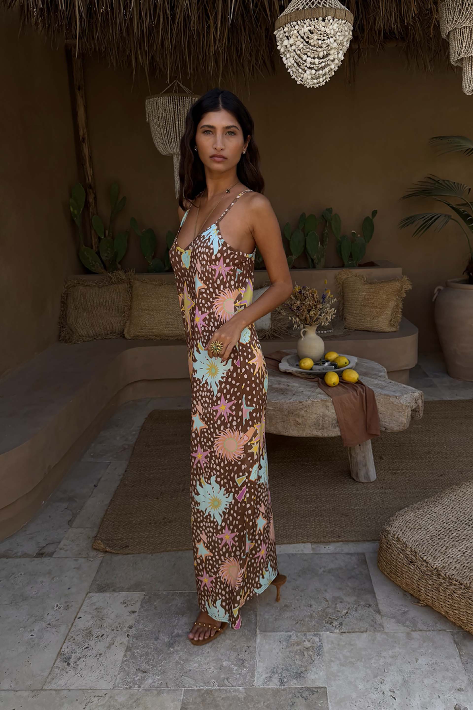 Star Fawn Aria Mesh Dress in a brown fawn spot print with sun and star motifs, styled in a rustic lounge setting.
