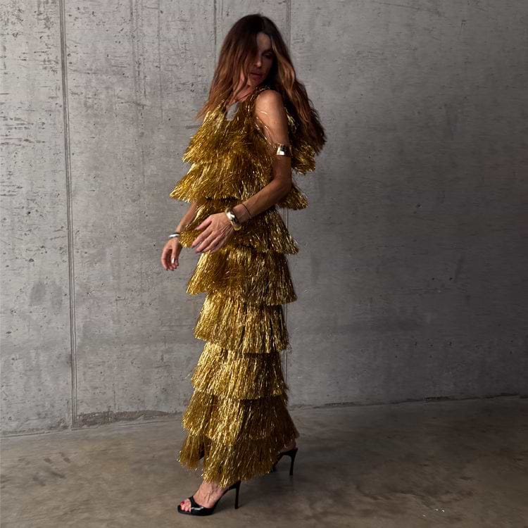Gold Fringe Dress with tiered foil tassels and a sleeveless silhouette, styled for a party against a concrete wall.