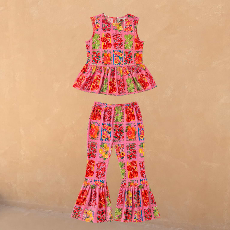 Girl's pink fruit print set with a sleeveless peplum top and matching frilled flared trousers in 100% cotton.