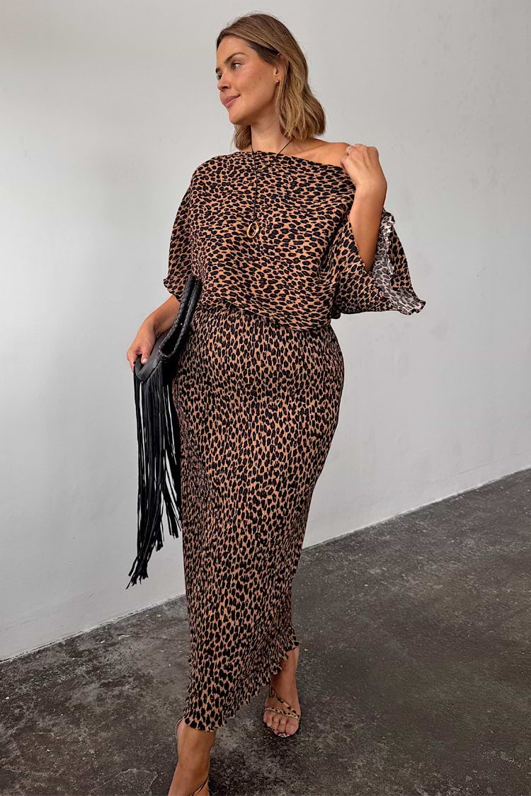 Lucia Leopard Tilly dress in plisse fabric, styled off-the-shoulder and paired with a black fringe clutch.
