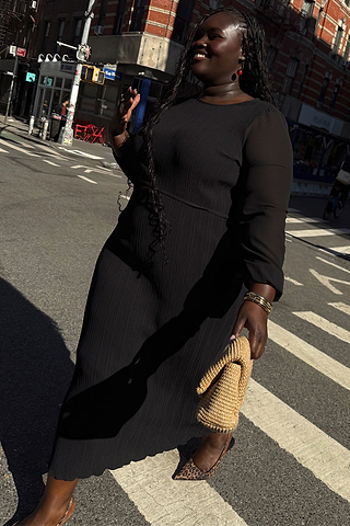Black Plisse Perrie Dress with sheer balloon sleeves and a tie waist, worn by a model for inclusive sizing on a city walk.