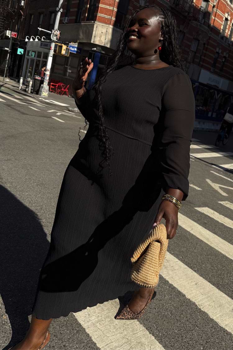 Black Plisse Perrie Dress with sheer balloon sleeves and a tie waist, worn by a model for inclusive sizing on a city walk.
