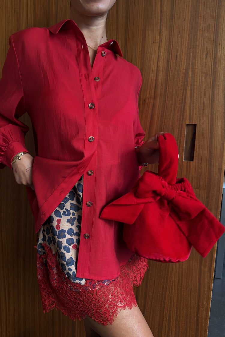 Red Velvet Bow Bag in red velvet featuring a statement bow, styled with a red shirt and leopard print skirt.