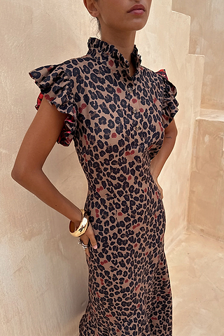 Cherry Leopard Remi Dress featuring a ruffled high neck and flutter sleeves in a leopard print with red cherries.