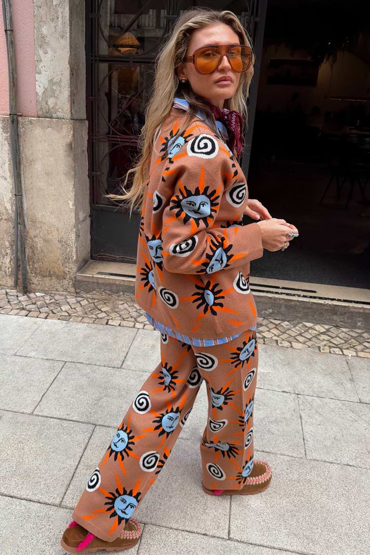 Tan Sun Trousers in a knit co-ord featuring Mediterranean sun and swirl motifs, styled on a model outdoors.