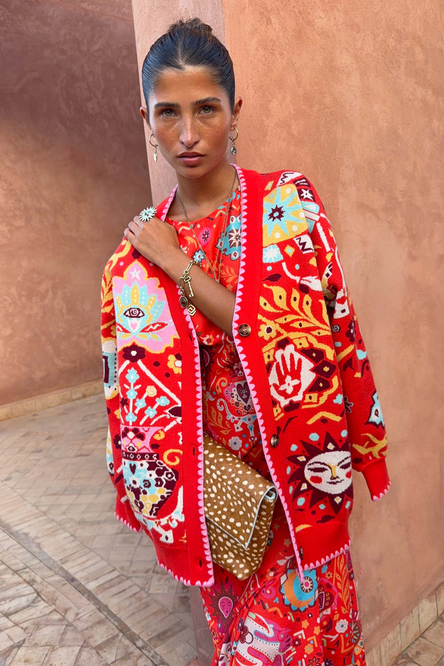 Red Tomato Tapestry Martha Cardigan with celestial sun motifs and pink blanket stitch edging on a model.