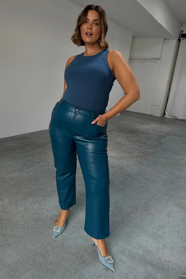Teal Vegan Leather Trousers in a straight leg fit, paired with a blue tank top and embellished heels.