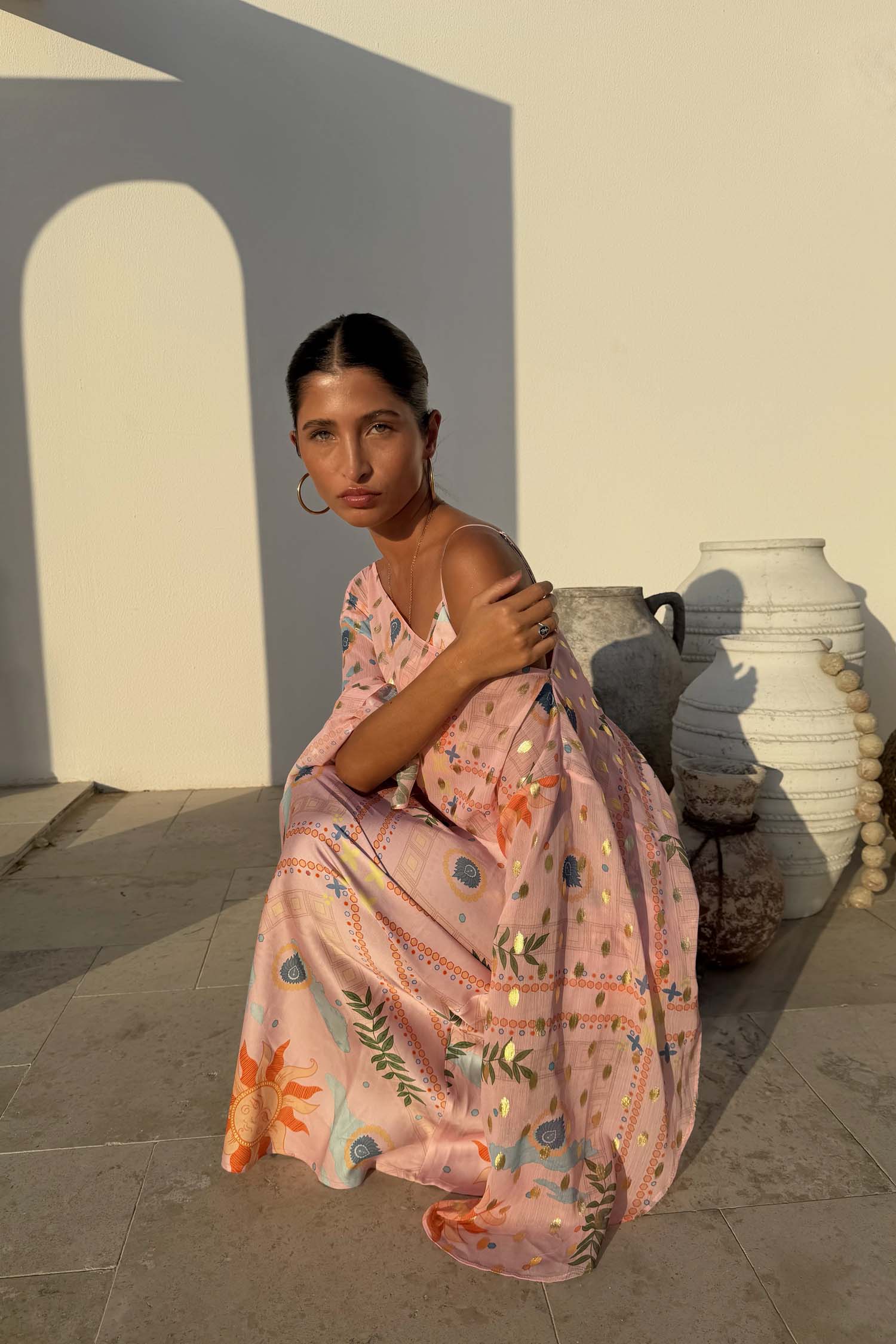 Pink Sun Anais Dress featuring iconic soleil motifs and gold flecks with a sheer off-shoulder top and satin-esque skirt.