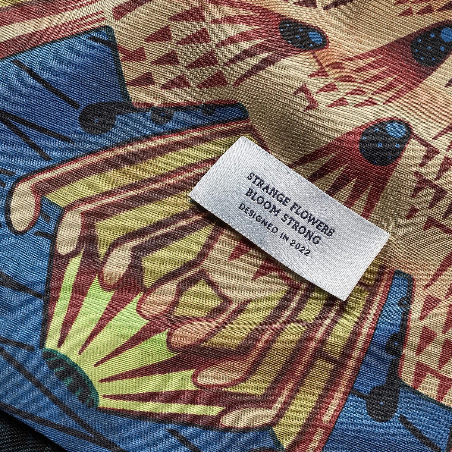 Patterned fabric under a white label with the text Strange flowers bloom strong