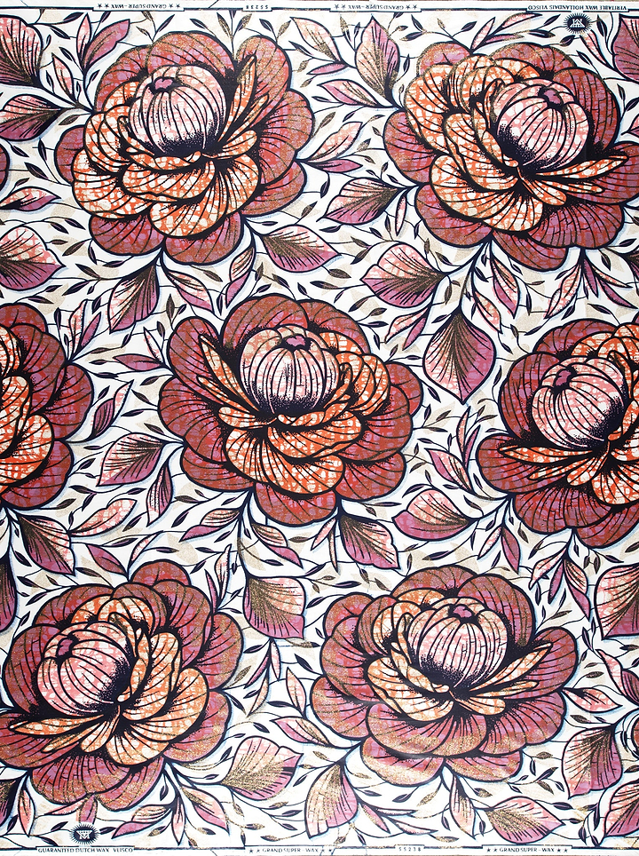 A close-up of a floral patterned fabric or wallpaper featuring large rose motifs in dusty rose, terracotta, and muted purple tones with black linework on a white background.