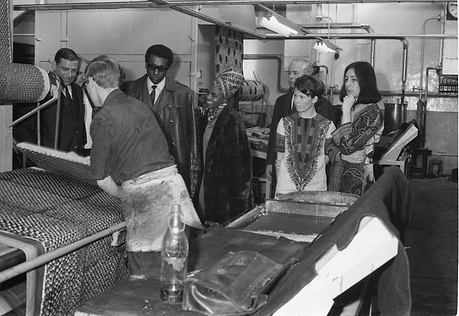 Black and white photo of visitors in a fabric factory