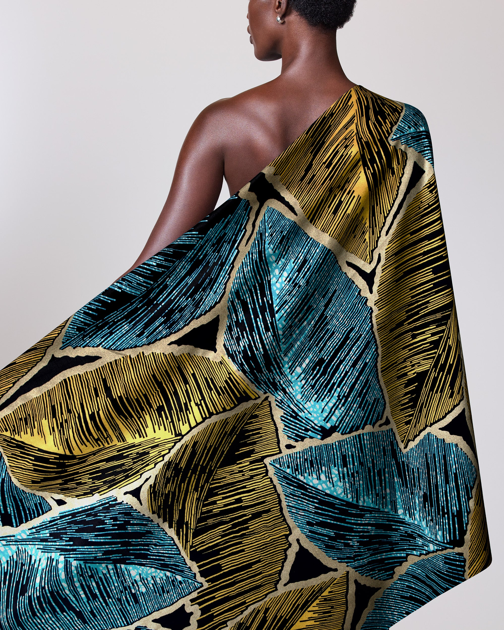 Woman wears vibrant one-shoulder wrap wax hollandais vl08946.010