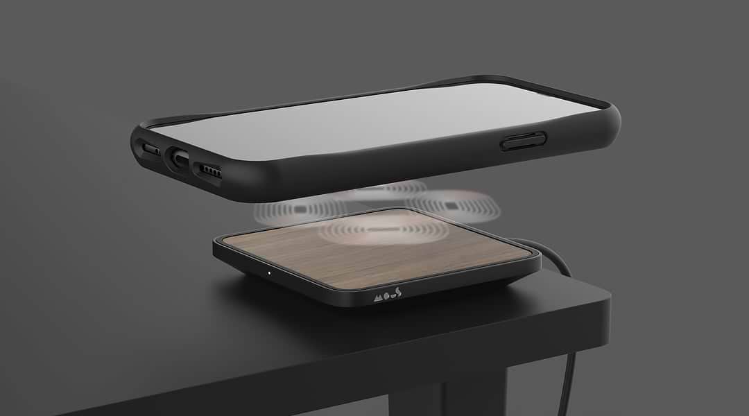 iPhone schwebt über einem Mous kabellosen Ladegerät auf einem Schreibtisch