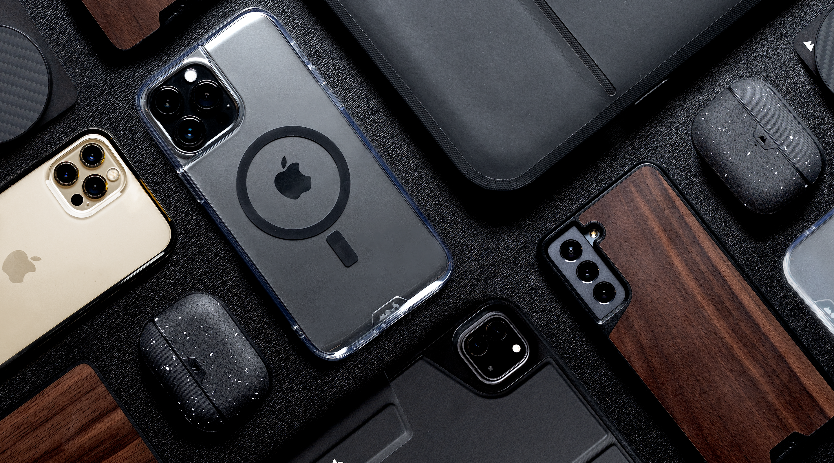 Flat lay of Mous tech accessories with MagSafe compatible cases, clear cases, a MacBook sleeve and AirPods cases