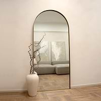 Full length arched gold extra large metal mirror leaning against wall