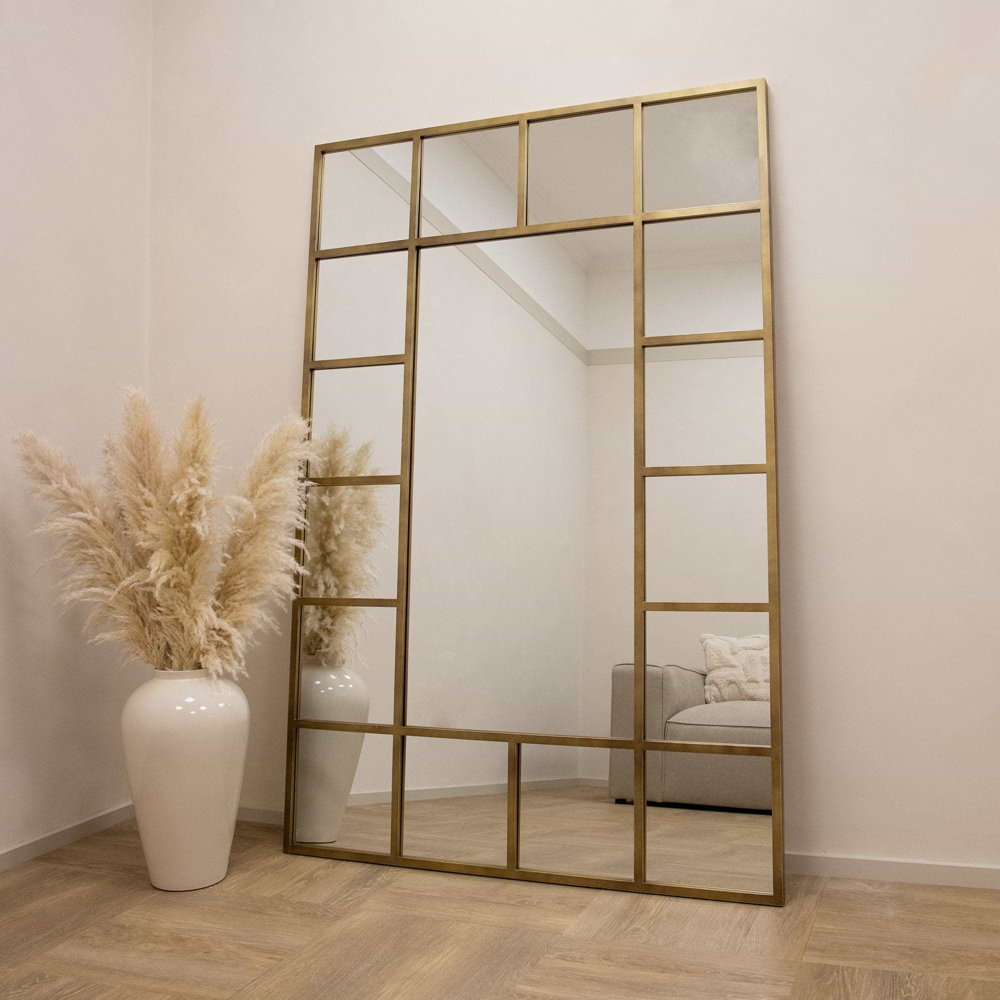 Gold industrial full length metal window mirror leaning against wall
