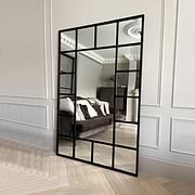 Black industrial full length metal window mirror leaning against wall