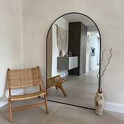 Black Full Length Arched Metal Mirror beside chair
