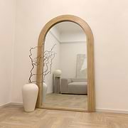 Full Length Arched Washed Wood Mirror beside ceramic vase