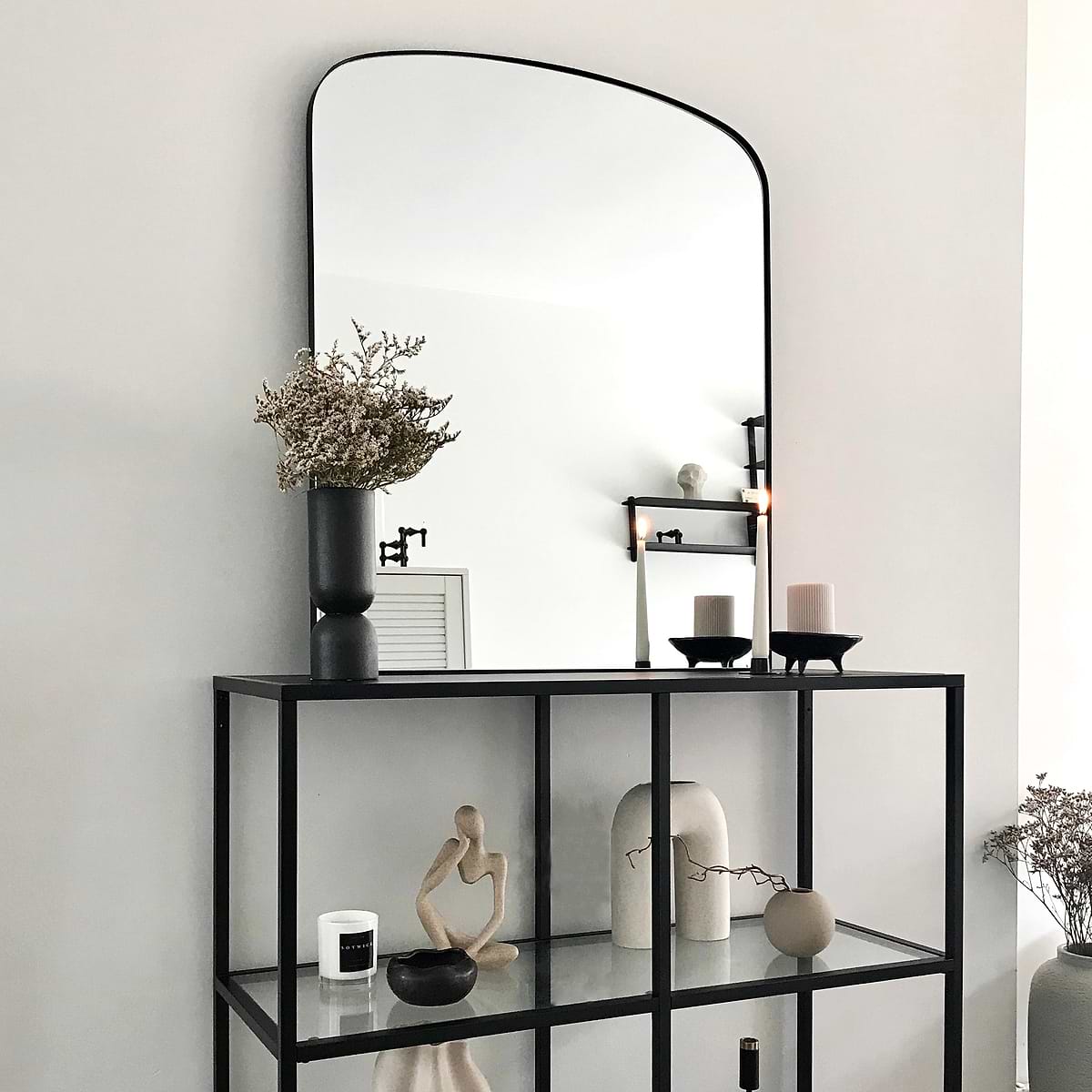 Black contemporary arched metal wall mirror displayed on console table