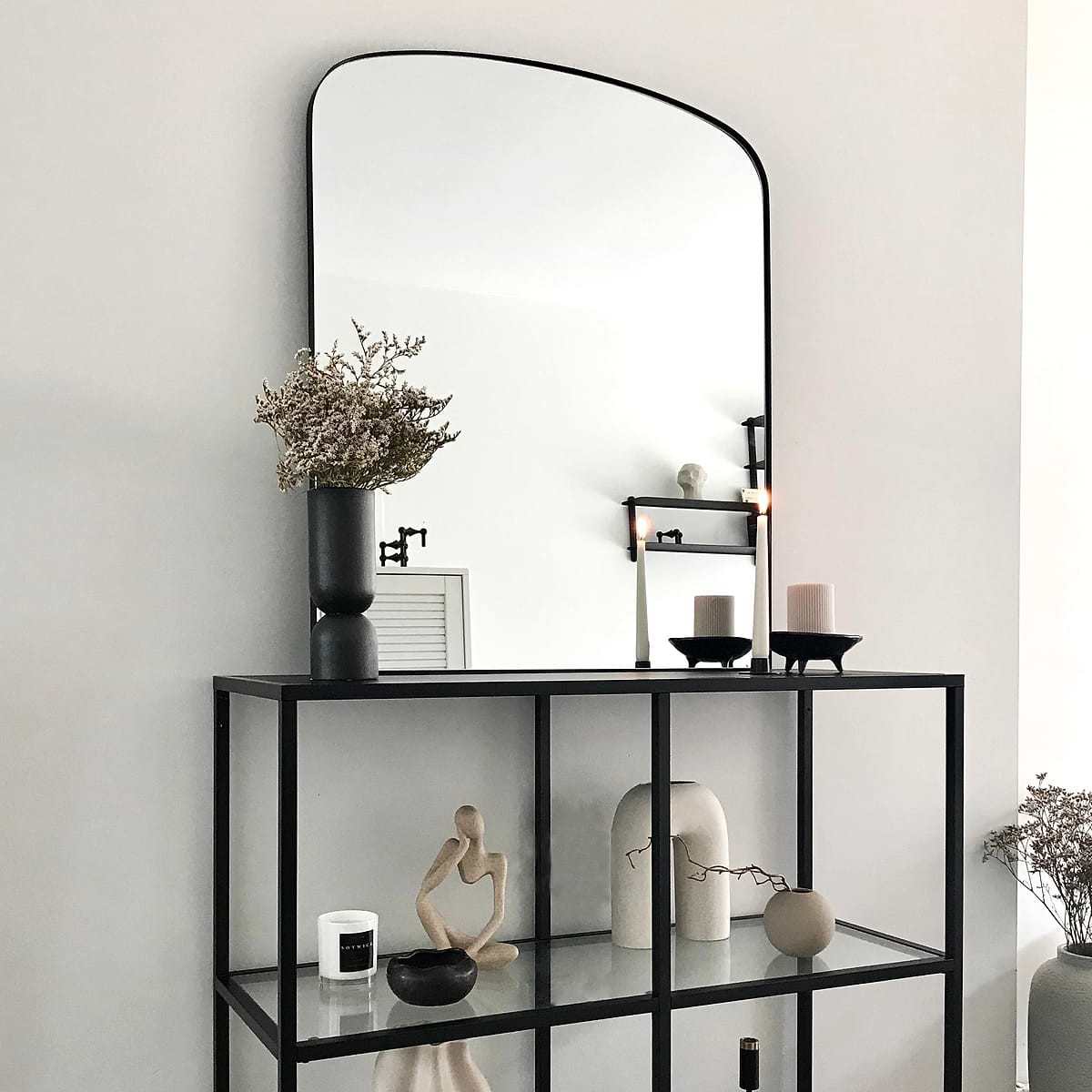 Black contemporary arched metal wall mirror displayed on console table