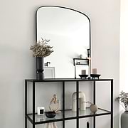 Black contemporary arched metal wall mirror displayed on console table