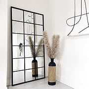 Full length large black metal window mirror beside vase
