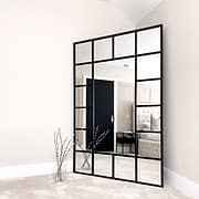 Black industrial full length metal window mirror in room corner