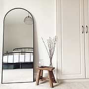 Black Full Length Arched Metal Mirror in bedroom beside bench