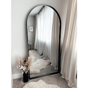 Full length arched black large metal mirror leaning against wall