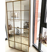 Full length large gold industrial metal window mirror leaning against wall