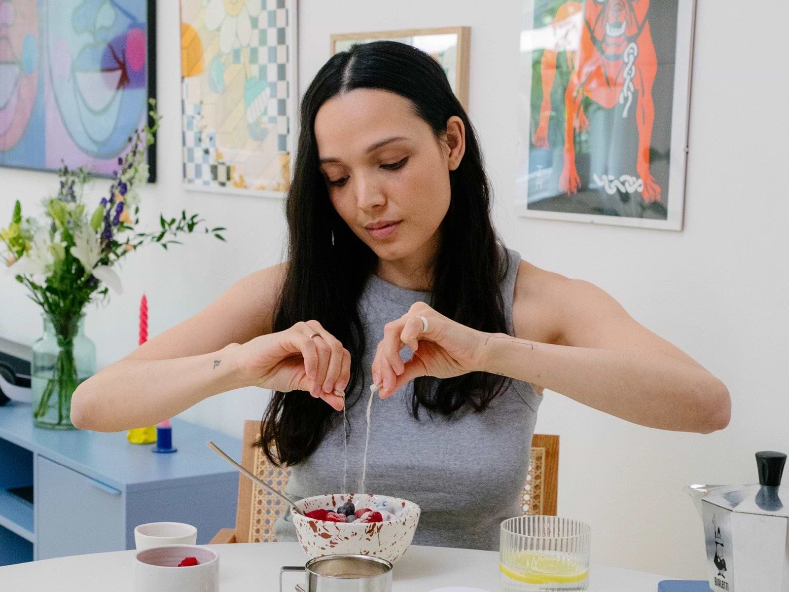 Woman preparing a bowl of berries at a colorful kitchen table.