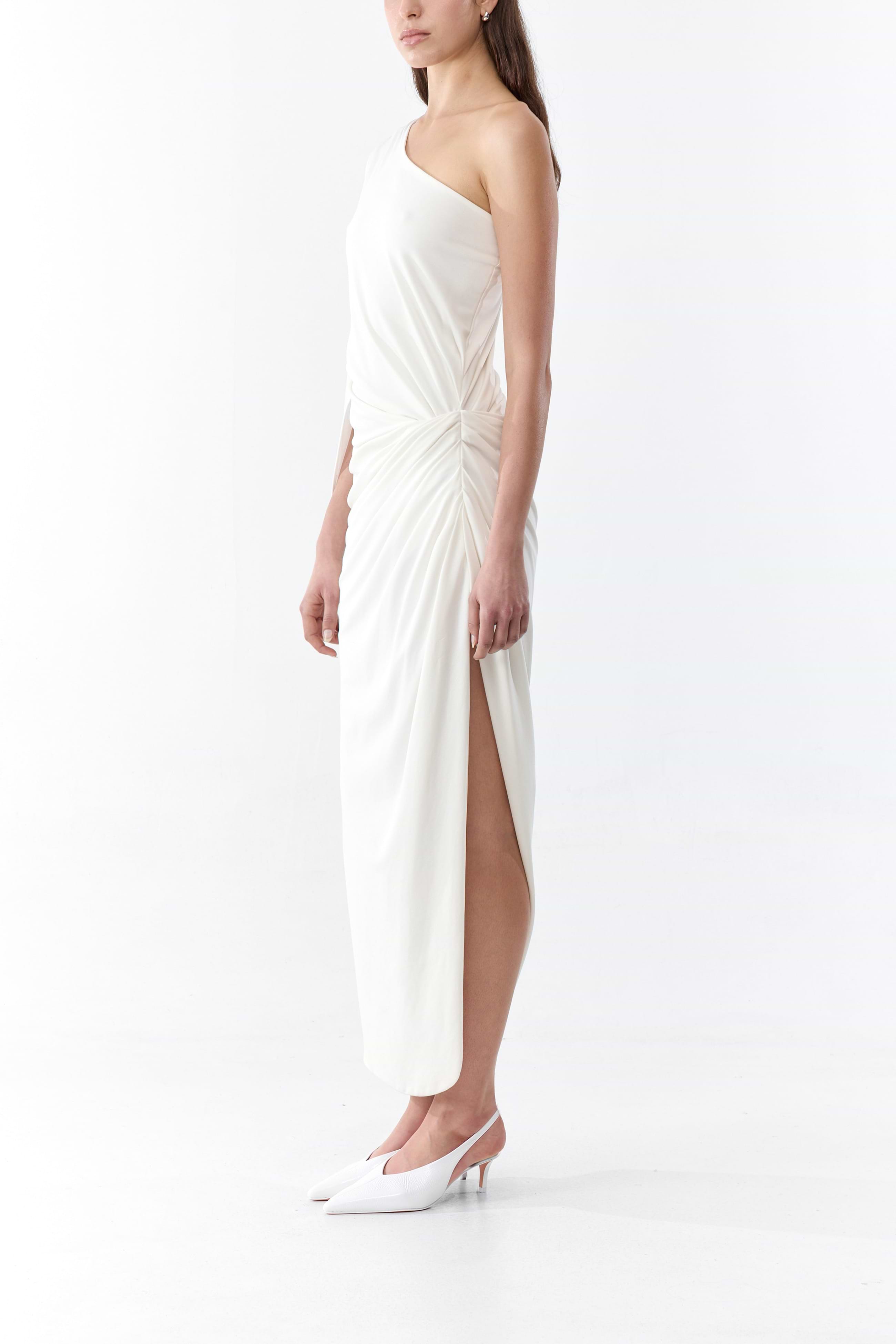 Woman wearing a white strapless dress with a high slit on a white background