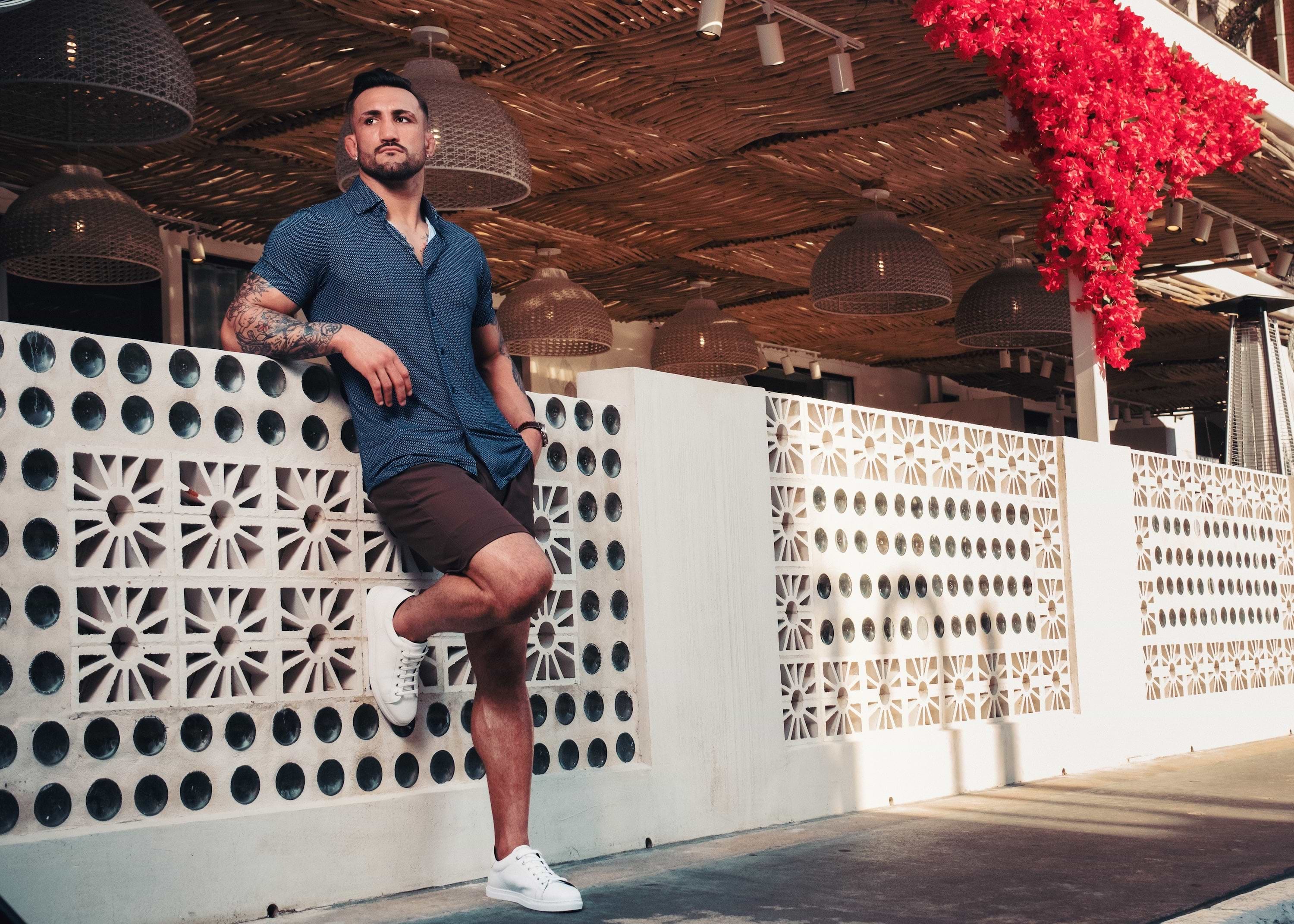 Man leaning against a decorative wall with red flowers in the background