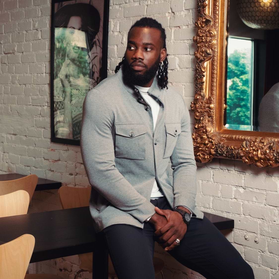 Man sitting at a table in a restaurant with a brick wall and framed pictures in the background