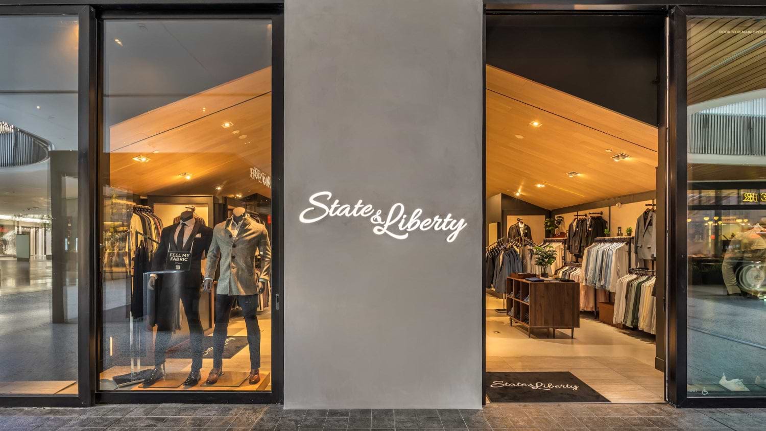 Storefront with 'State of Liberty' sign, displaying clothing inside.