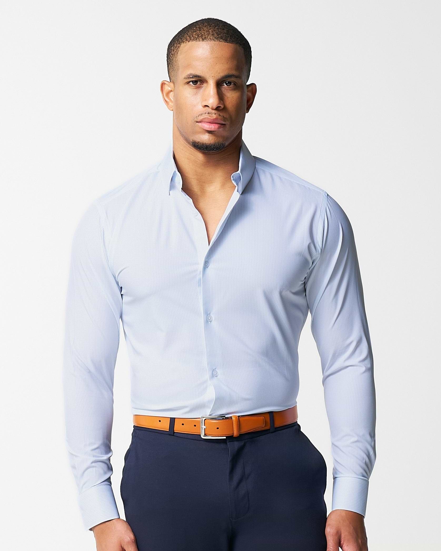 Man wearing a light blue dress shirt and navy pants with an orange belt on a white background