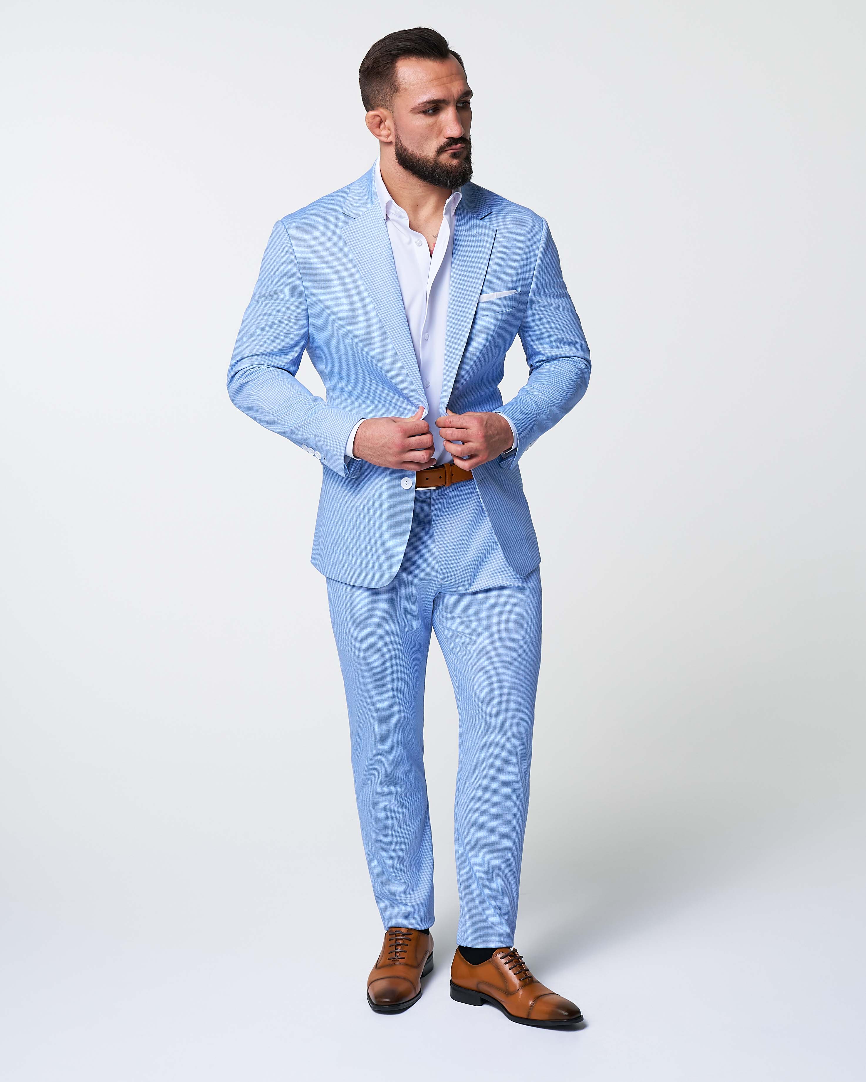 Man wearing a light blue suit with brown shoes on a white background