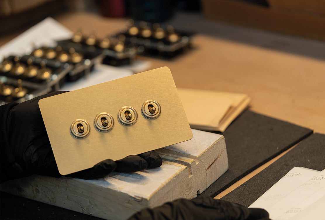 A person carefully packaging a '4G Two Way Toggle Switch' product in an antique brass finish.