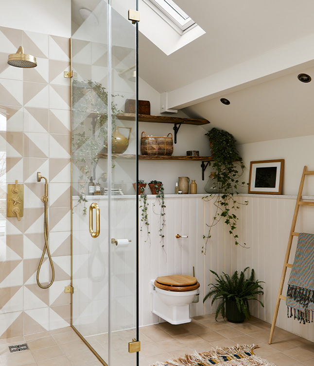 Modern bathroom featuring a glass shower, natural wood accents, greenery, and elegant fixtures against a geometric tile backdrop.