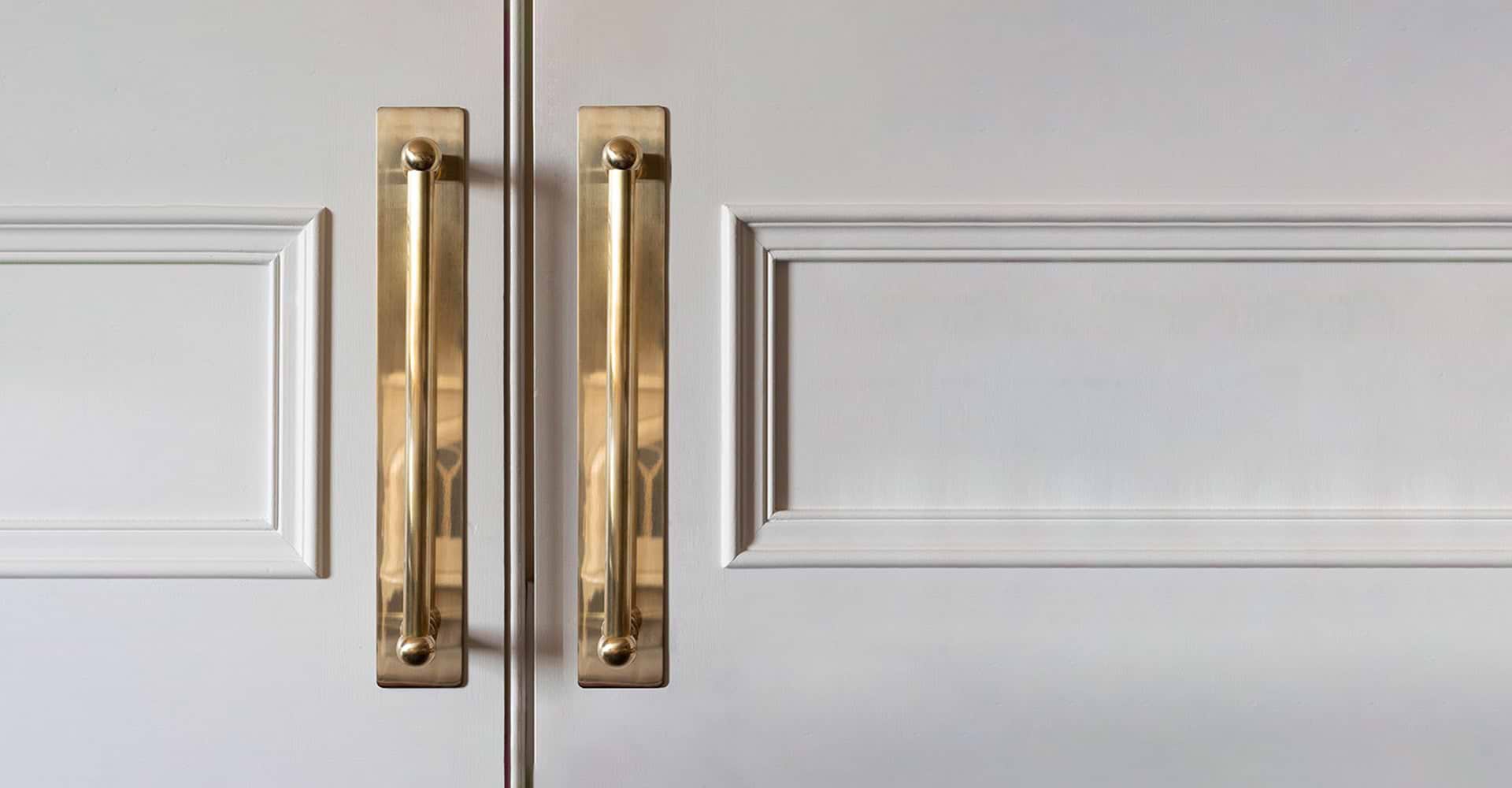 Close-up of elegant white cabinet doors featuring detailed paneling and sleek gold handles, adding a touch of sophistication.