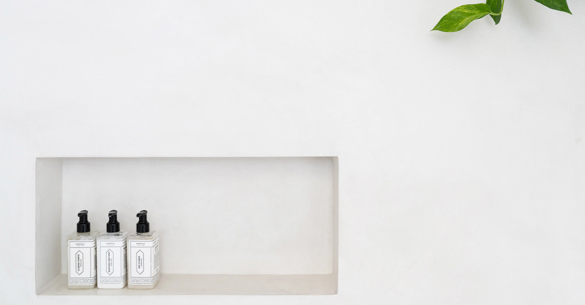Three elegant, labeled soap dispensers on a minimalist white wall shelf, conveying a clean, modern aesthetic.
