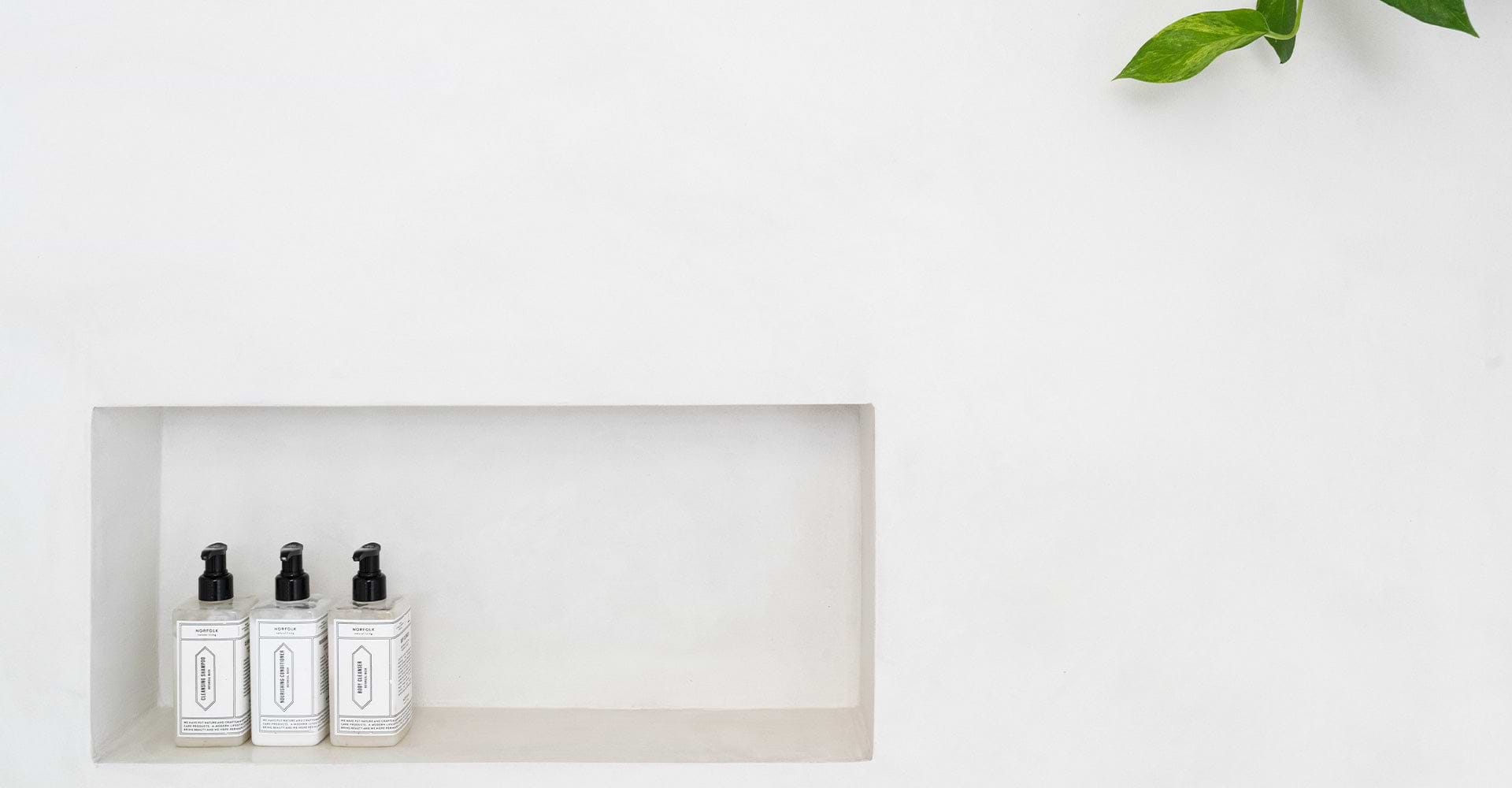 Three elegant, labeled soap dispensers on a minimalist white wall shelf, conveying a clean, modern aesthetic.