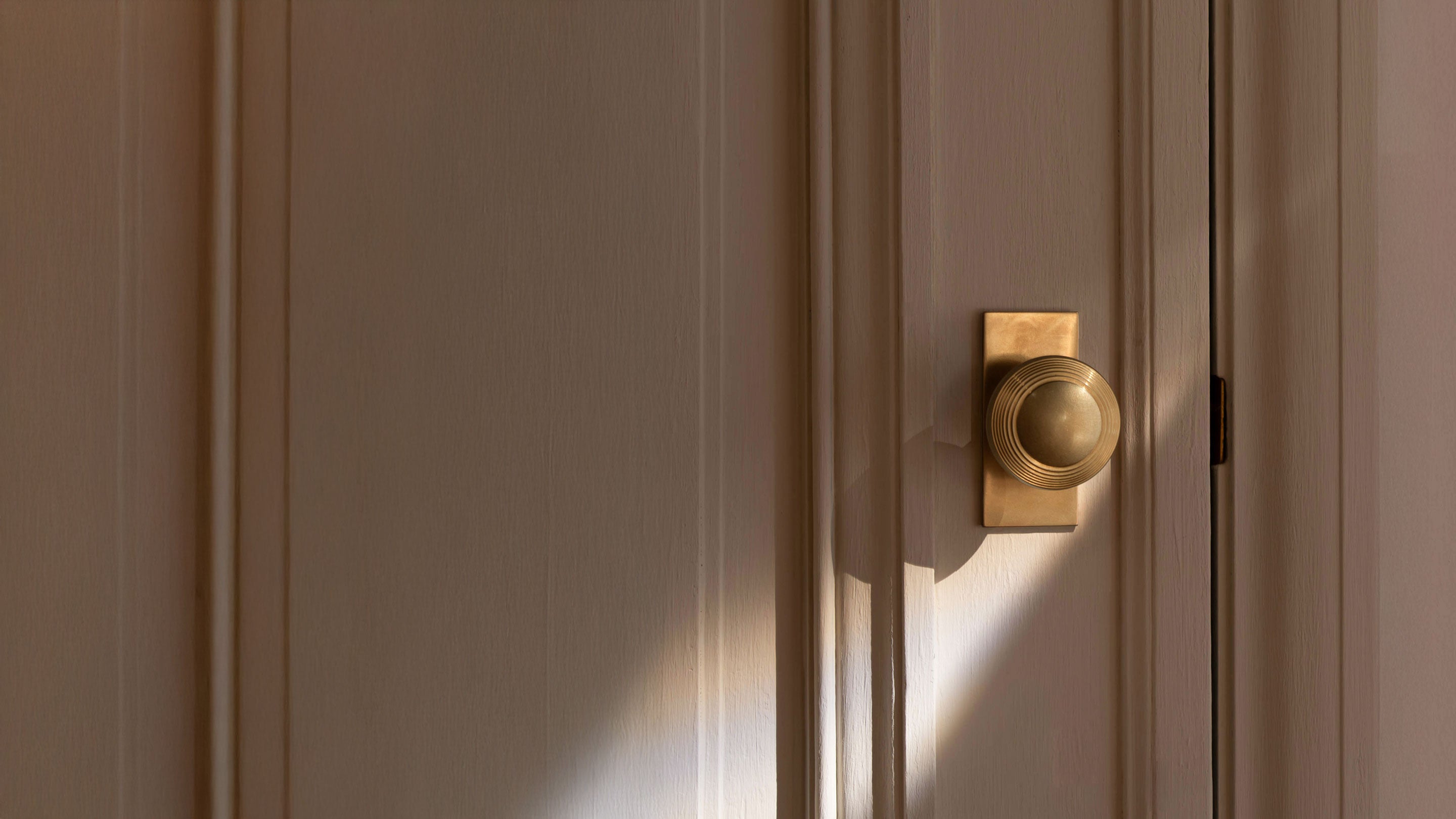 Close-up of a wooden door with a brass handle and latch, featuring text about a buying guide for door furniture.