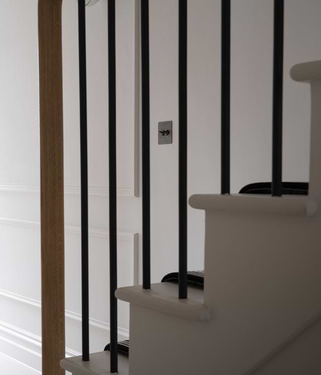 A view of a staircase with white walls, black railing, and a wooden door frame, creating a modern and minimalist aesthetic.