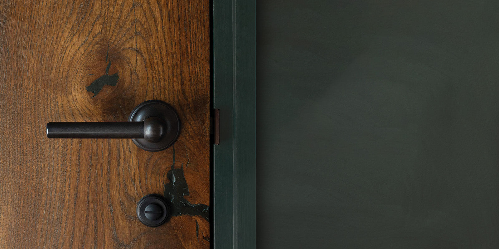 Close-up of a rustic wooden door featuring a black lever handle and keyhole, with text about door furniture details.