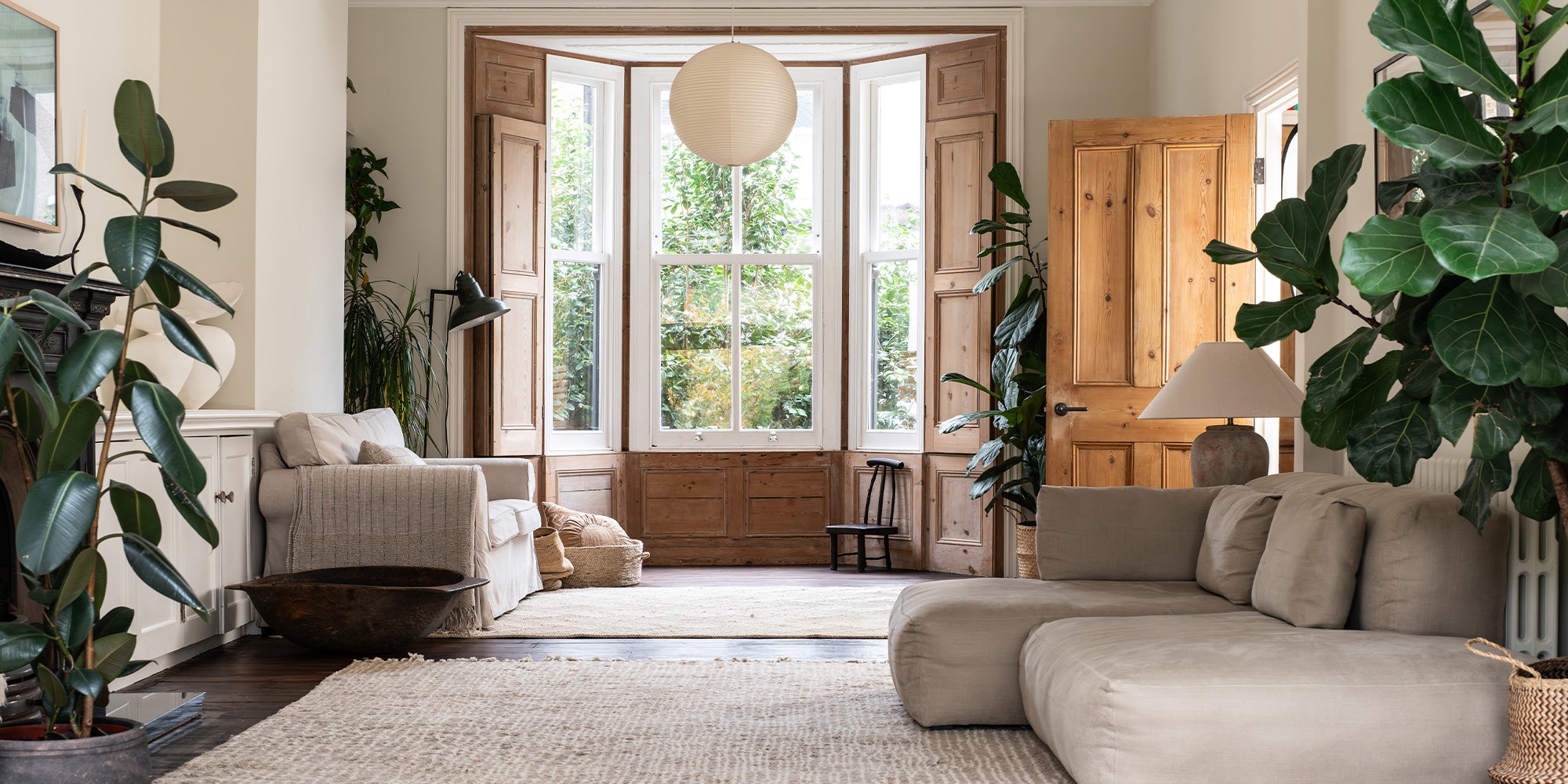 A living room flooded with natural light, filled with plants and cushy furnishings