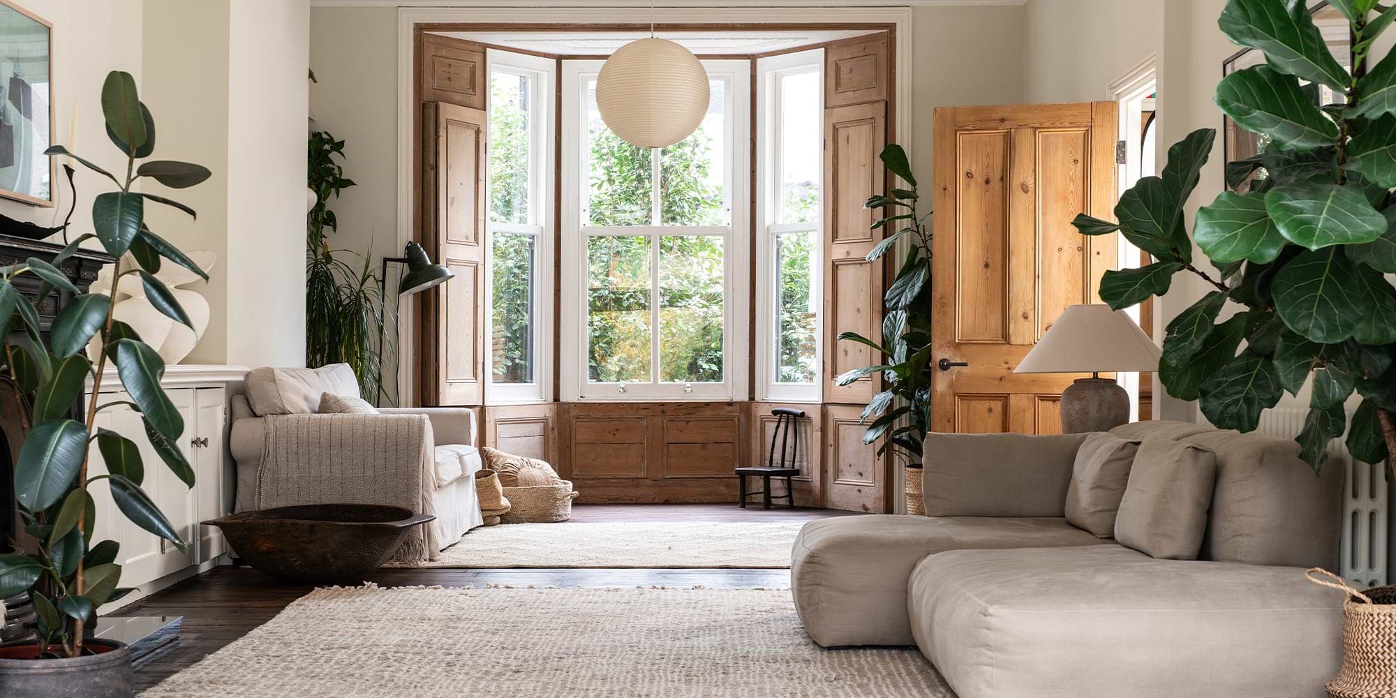 A living room flooded with natural light, filled with plants and cushy furnishings